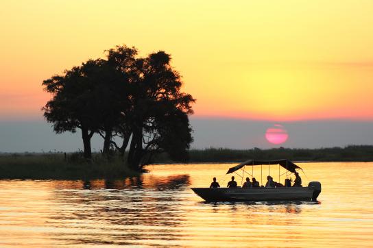 Sundowner auf dem Chobe River. Bei Sonnenuntergang mit dem Boot über den Chobe Fluss in Botswana fahren
